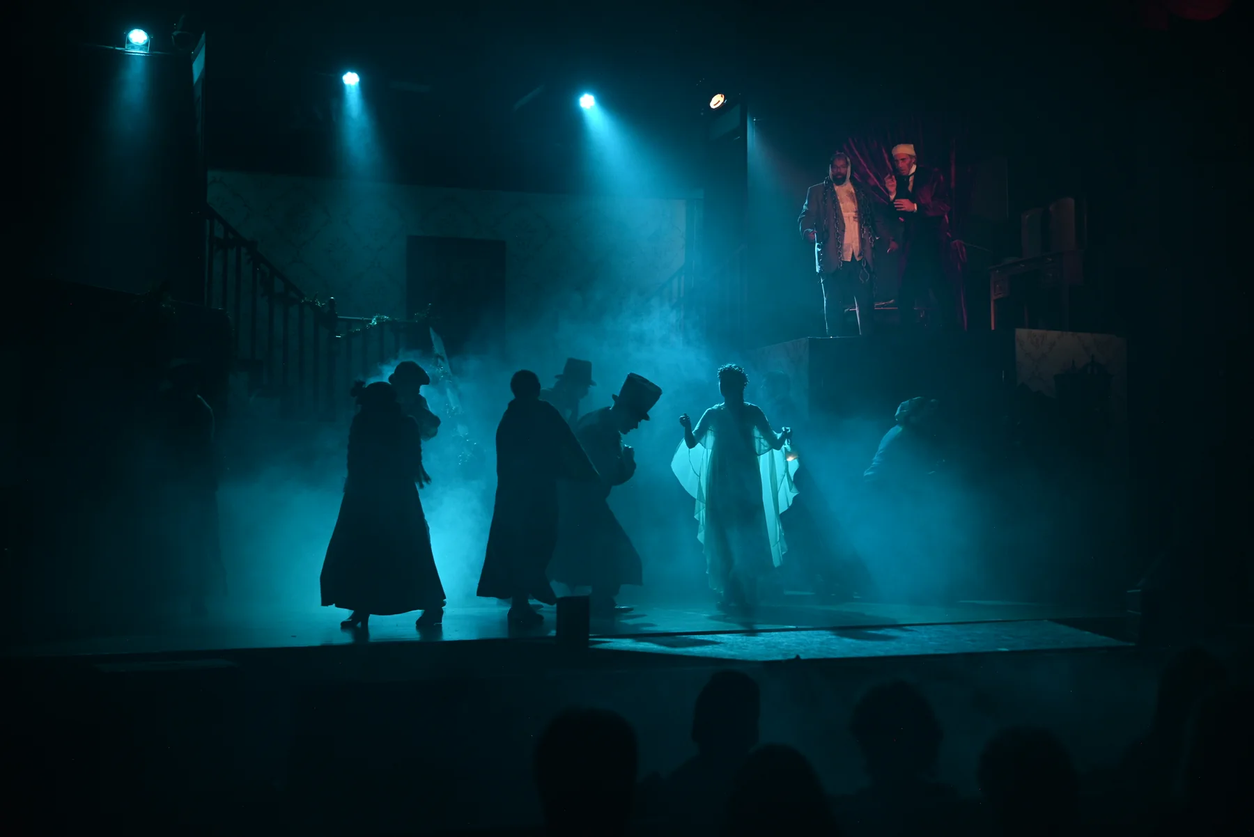 Ghostly silhouettes emerge through blue-lit fog in the 2025 production.